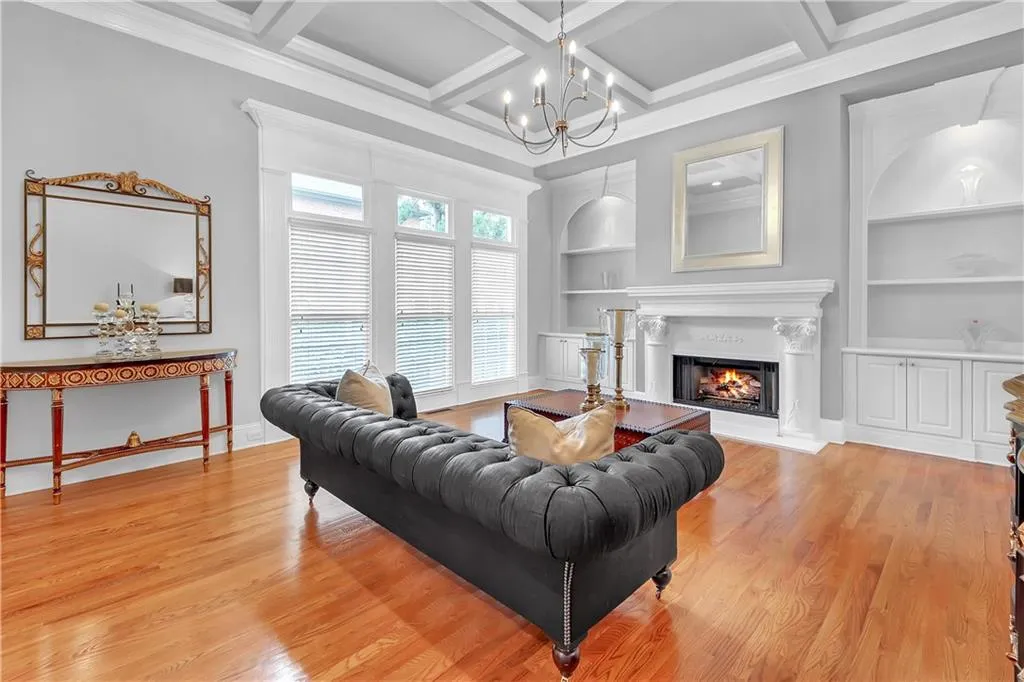 Living room featuring built in features, coffered ceiling, light hardwood / wood-style floors, and a chandelier