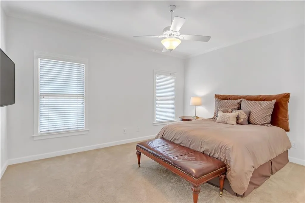 Bedroom with ornamental molding, ceiling fan, carpet floors, and multiple windows