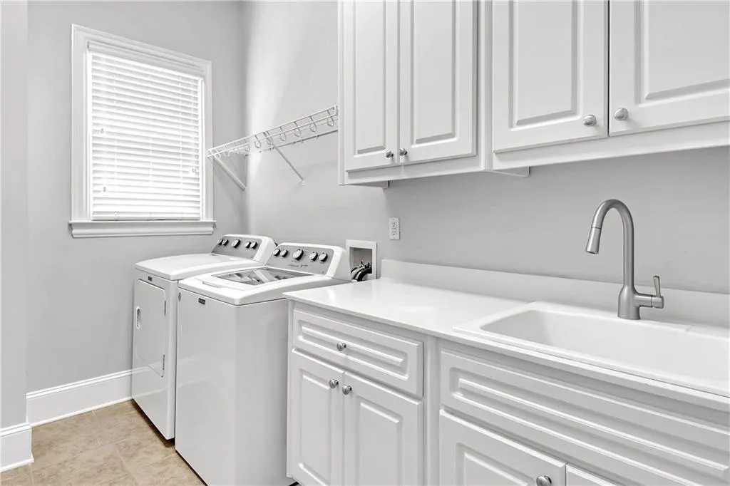 Washroom featuring cabinets, light tile flooring, separate washer and dryer, hookup for a washing machine, and sink