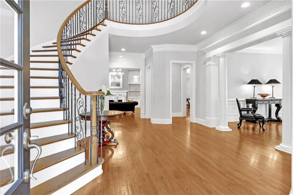 Foyer entrance featuring light hardwood / wood-style floors, crown molding, and ornate columns