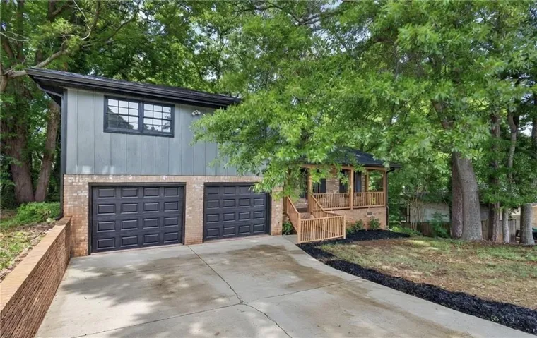 Split-level residence featuring a brick and siding exterior with a two-car garage