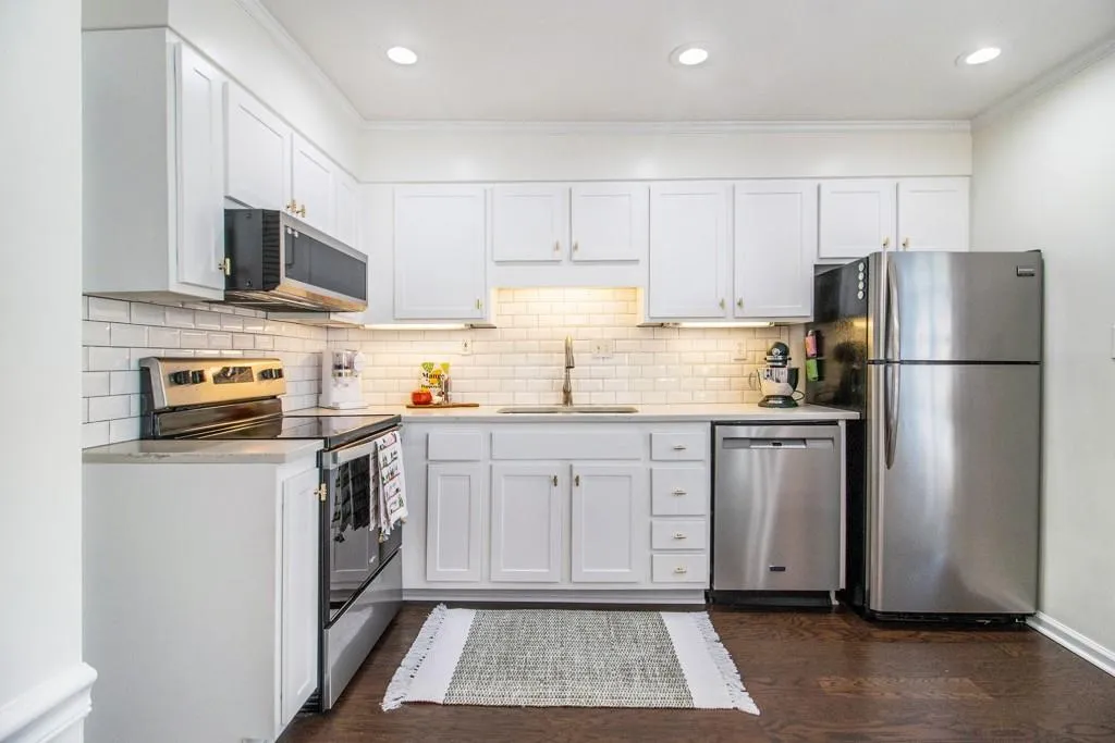 The kitchen and dining area shine with quartz countertops, classic subway tile backsplash, stainless steel appliances, gold accents, pantry space, and a breakfast bar perfect for casual dining.