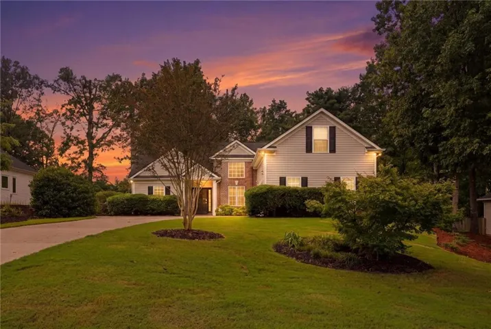Traditional style residence featuring a two-car driveway, mature landscaping, and an expansive front lawn