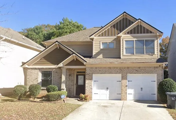 Two-story residence featuring brick and siding facade, dual garage doors, and a concrete driveway