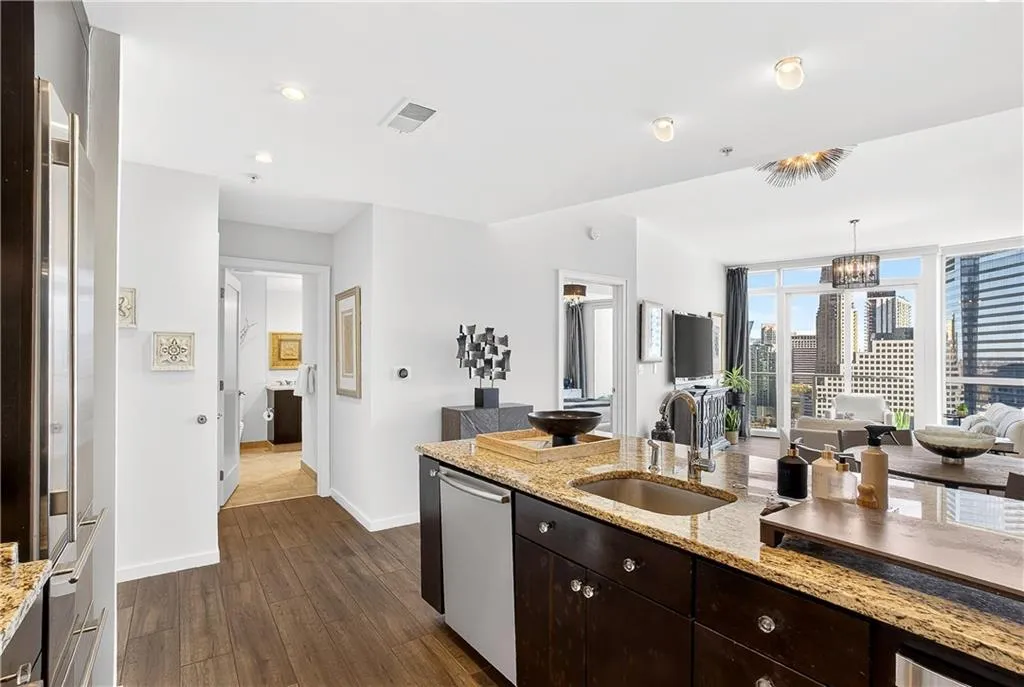 Kitchen with dark wood finish cabinets, light stone counters, open floor plan, and dark wood-style floors
