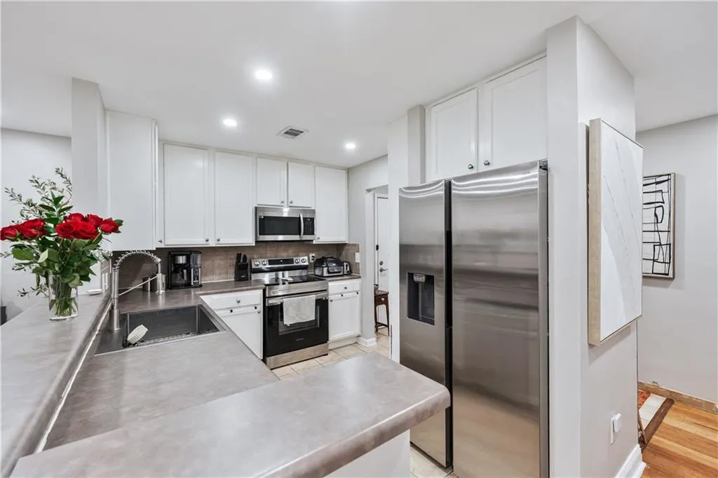Kitchen with appliances with stainless steel finishes, backsplash, white cabinets, recessed lighting, and light tile patterned floors