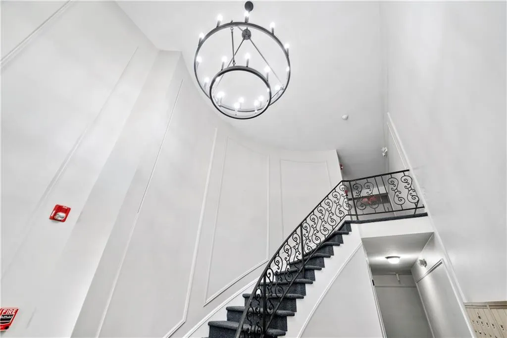 Stairway featuring a decorative wall, a chandelier, and a high ceiling