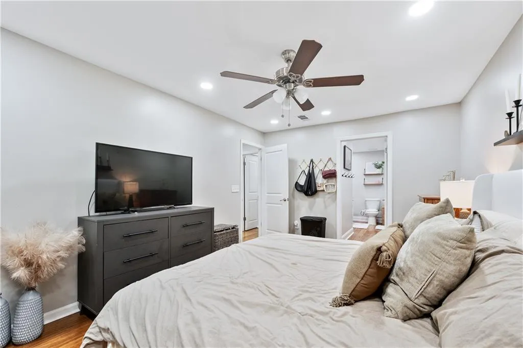 Bedroom featuring wood finished floors, recessed lighting, ceiling fan, and ensuite bathroom
