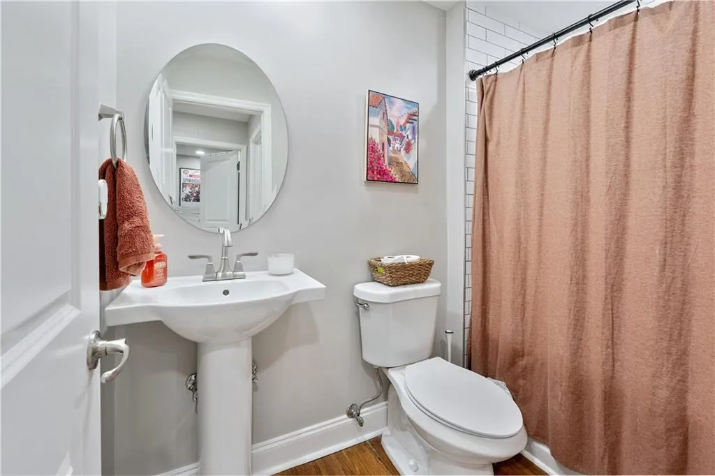Bathroom with a shower with shower curtain and wood finished floors