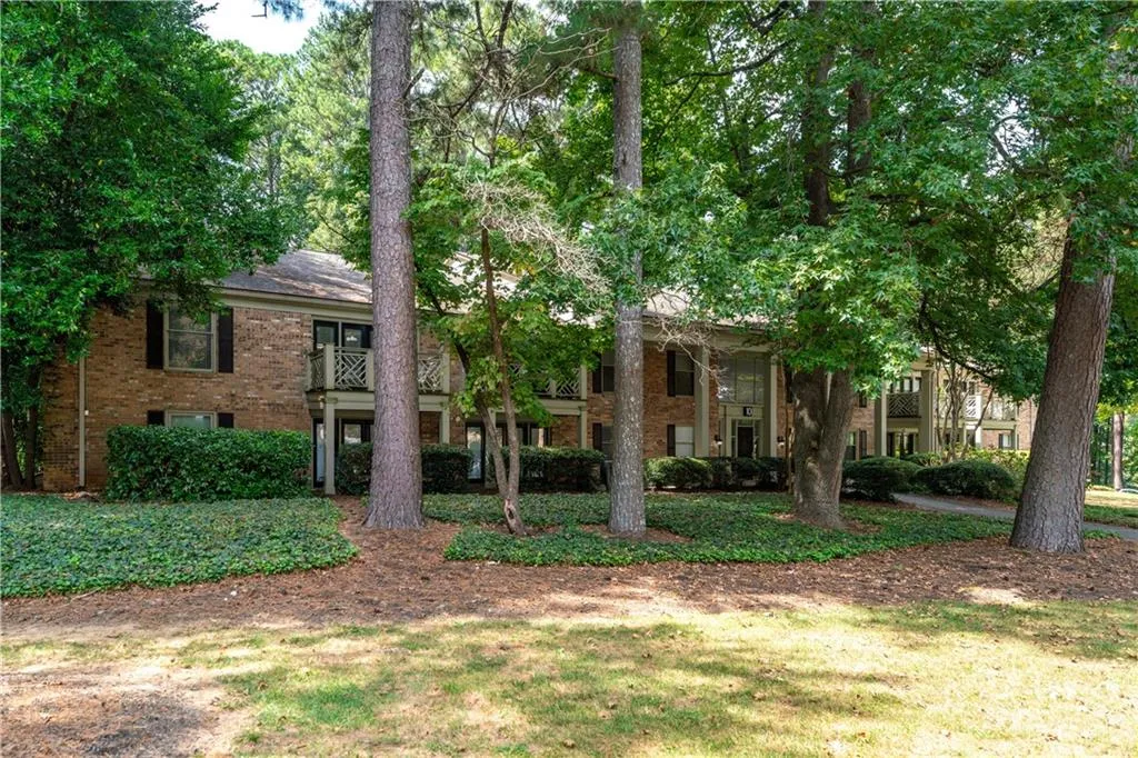 View of front of home with a balcony, brick siding, and a front yard