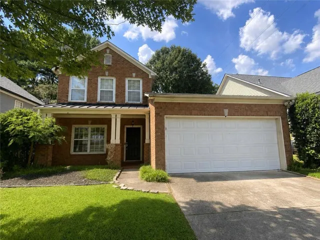 Brick exterior with a covered entry, gabled roofline, front-facing garage, and a concrete driveway