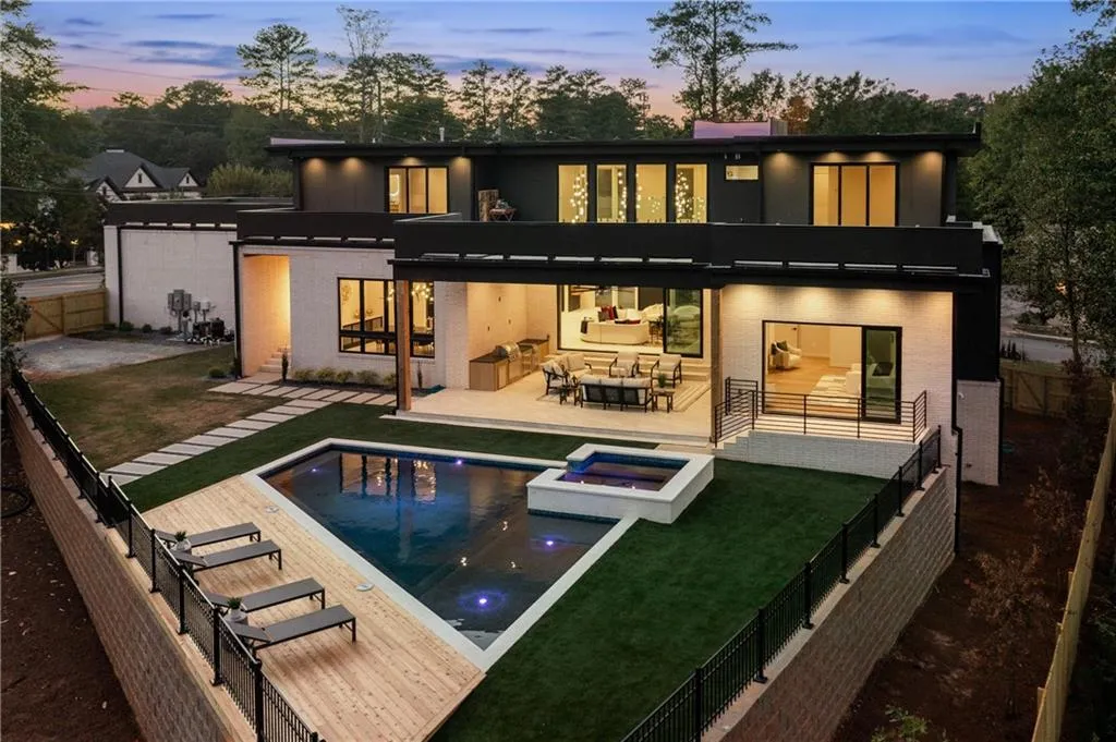 Back of house at dusk featuring a fenced backyard, a patio area, a pool with connected hot tub, brick siding, and outdoor lounge area Back of house at dusk featuring a fenced backyard, a patio area, a pool with connected hot tub, brick siding, and outdoor lounge area