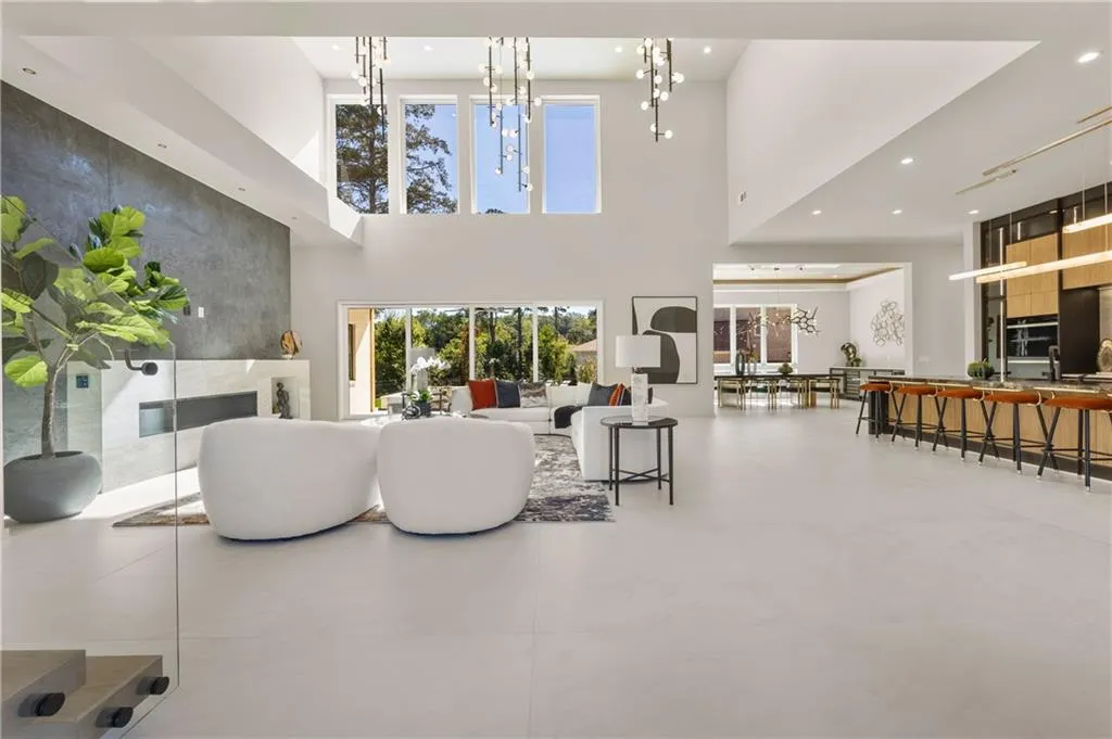 Spectacular two-story living room open to the kitchen, featuring sliding glass doors that fully open to the pool, a custom tiled fireplace with Taj Mahal quartzite, and 48x48 designer tile flooring for ultimate modern luxury. Spectacular two-story living room open to the kitchen, featuring sliding glass doors that fully open to the pool, a custom tiled fireplace with Taj Mahal quartzite, and 48x48 designer tile flooring for ultimate modern luxury.