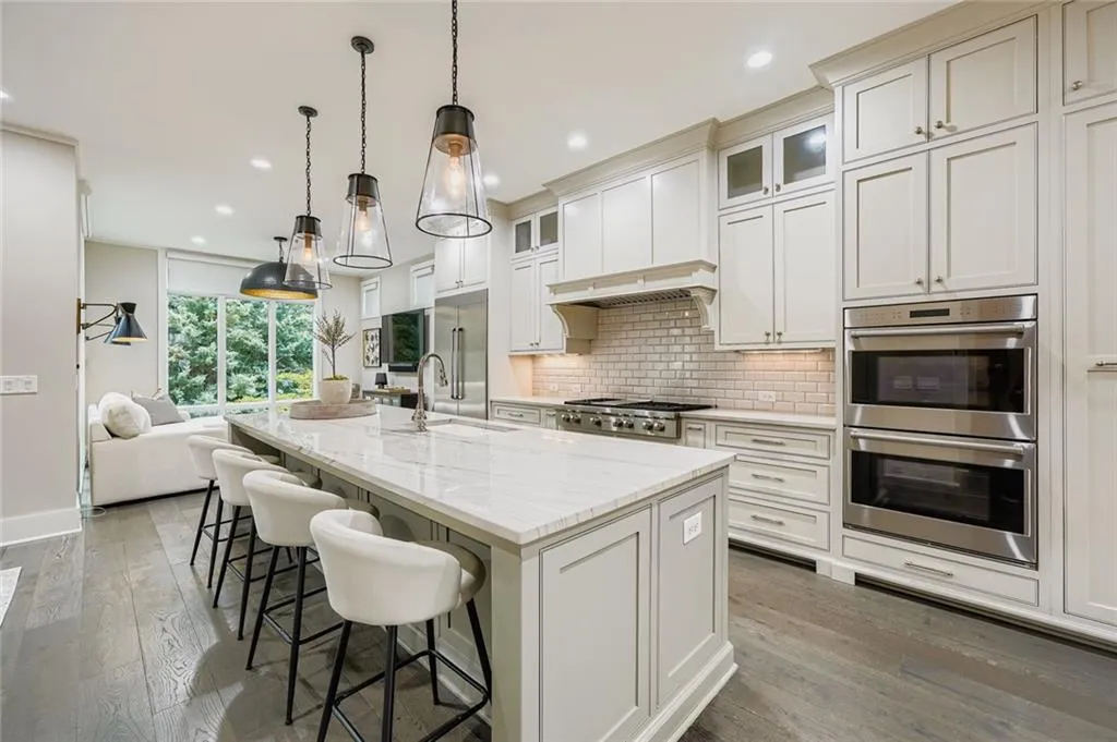 Kitchen featuring appliances with stainless steel finishes, backsplash, hardwood / wood-style floors, a kitchen island with sink, and recessed lighting