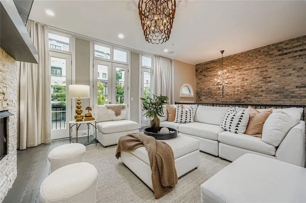 Living area featuring a chandelier, brick wall, a stone fireplace, hardwood / wood-style floors, and recessed lighting