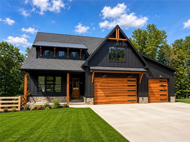 Modern farmhouse exterior with dark vertical siding, wood-finish garage doors, stone veneer accents, wood support beams, and a dormer with a metal roof