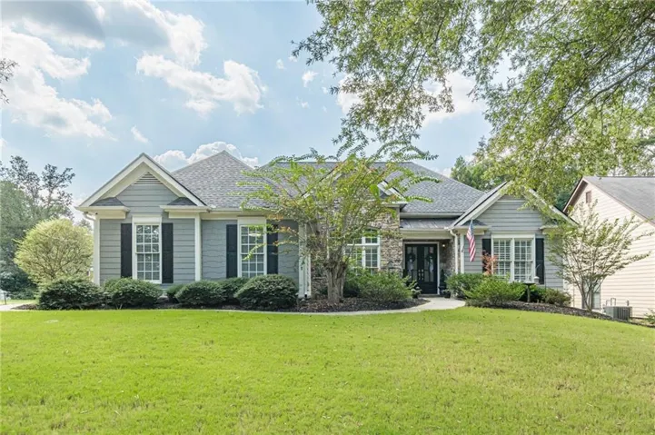 Single-story residence featuring siding and stone accents, a gabled roofline, front landscaping, and a covered entry