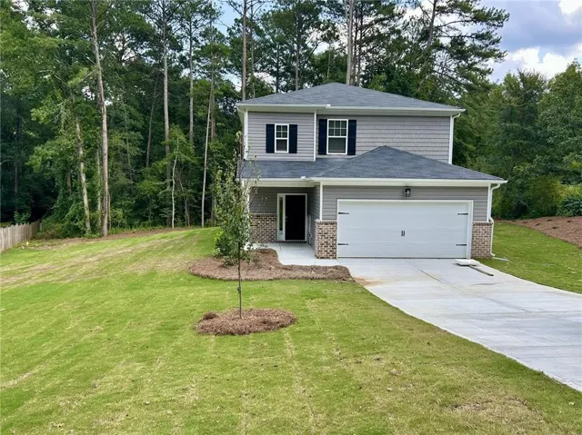 Two-story residence featuring a gray siding exterior, brick accents, and a two-car garage
