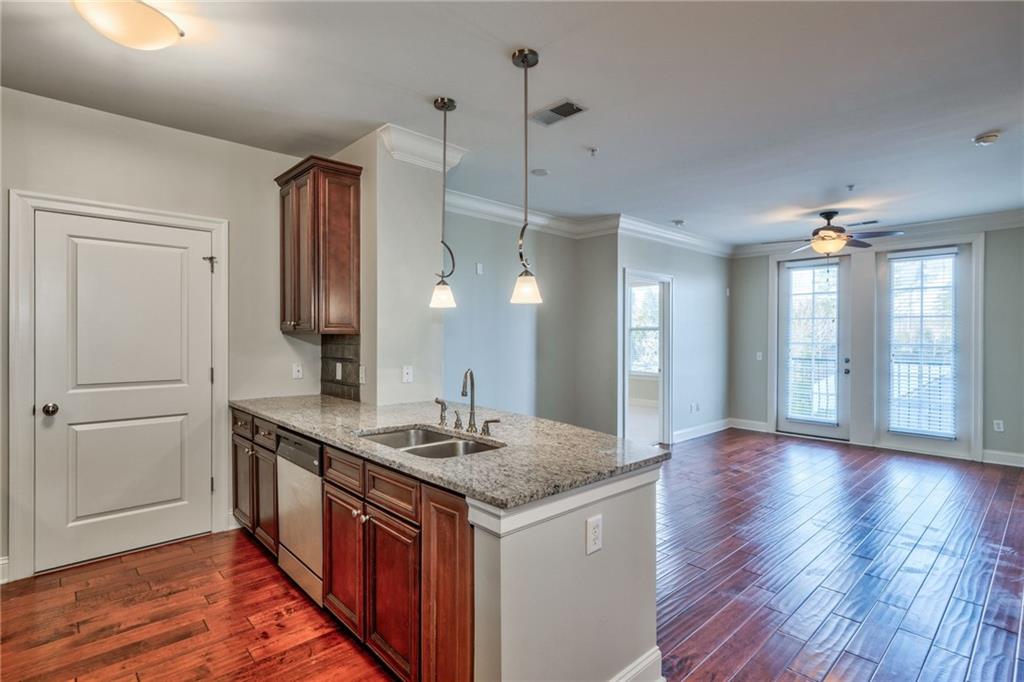 Kitchen featuring hanging light fixtures, stainless steel dishwasher, ceiling fan, sink, and dark hardwood / wood-style floors