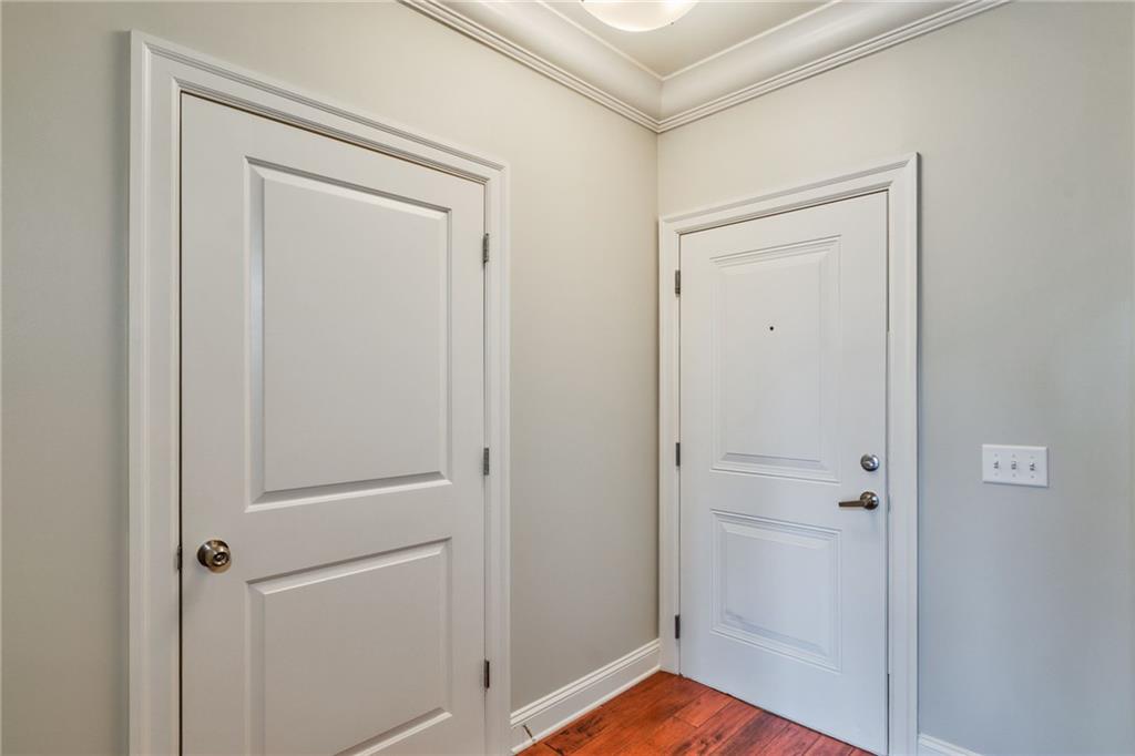 Doorway featuring crown molding and dark wood-type flooring