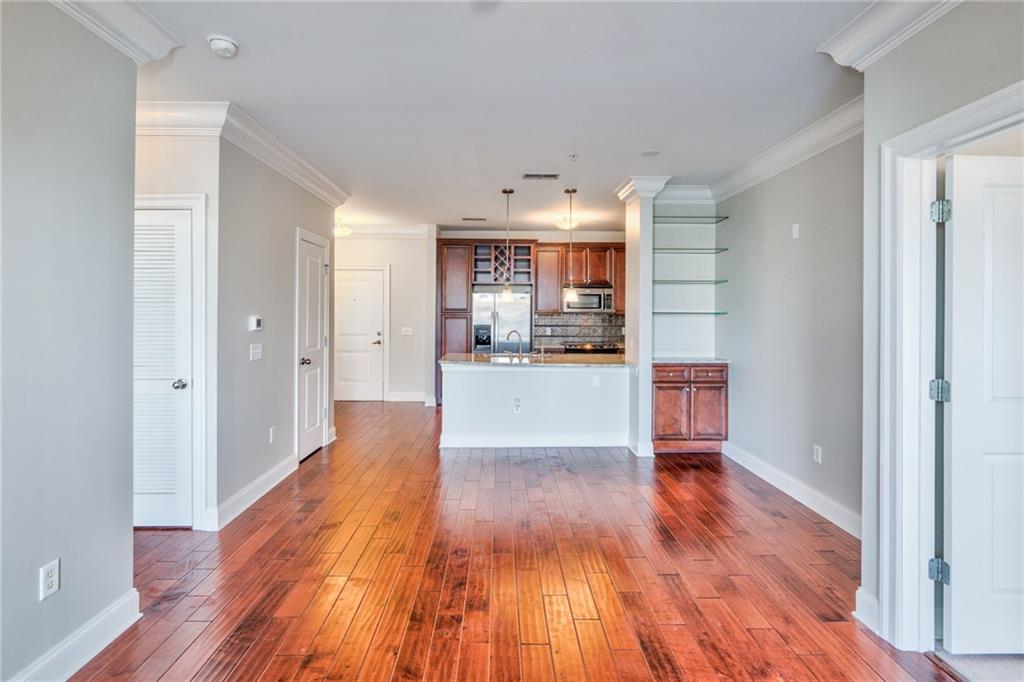 Kitchen featuring dark hardwood / wood-style flooring, light stone countertops, decorative light fixtures, appliances with stainless steel finishes, and tasteful backsplash