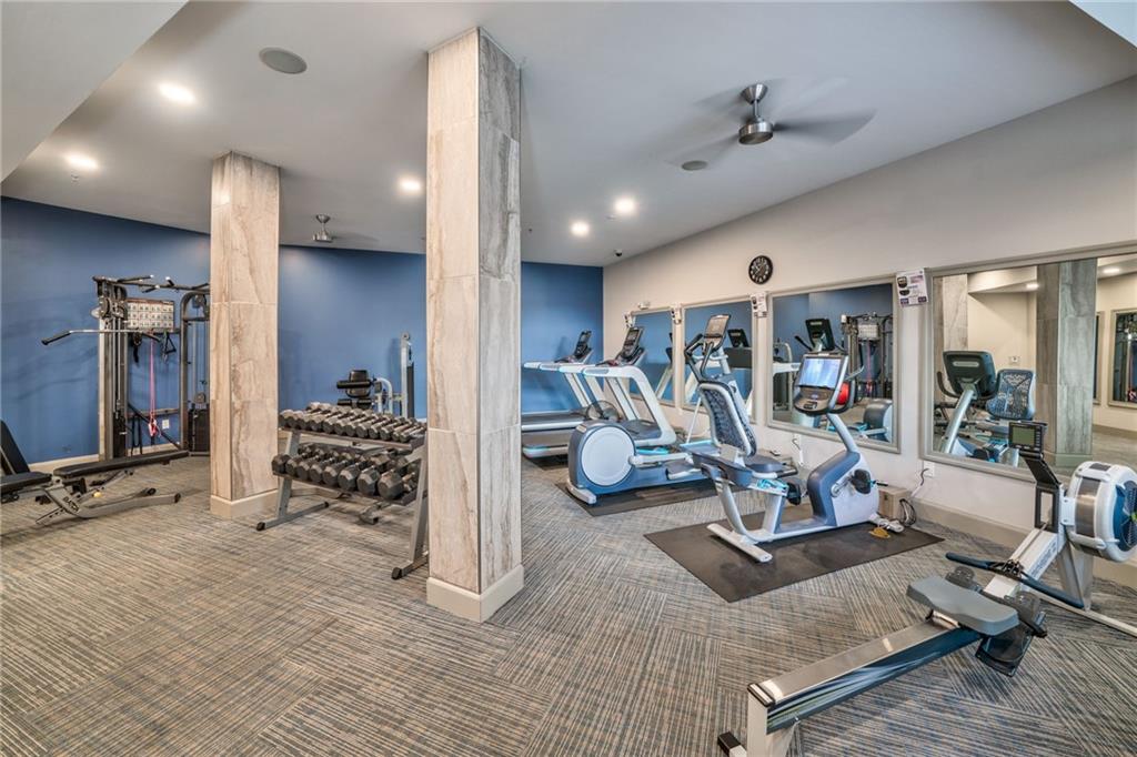 Exercise room featuring dark colored carpet and ceiling fan