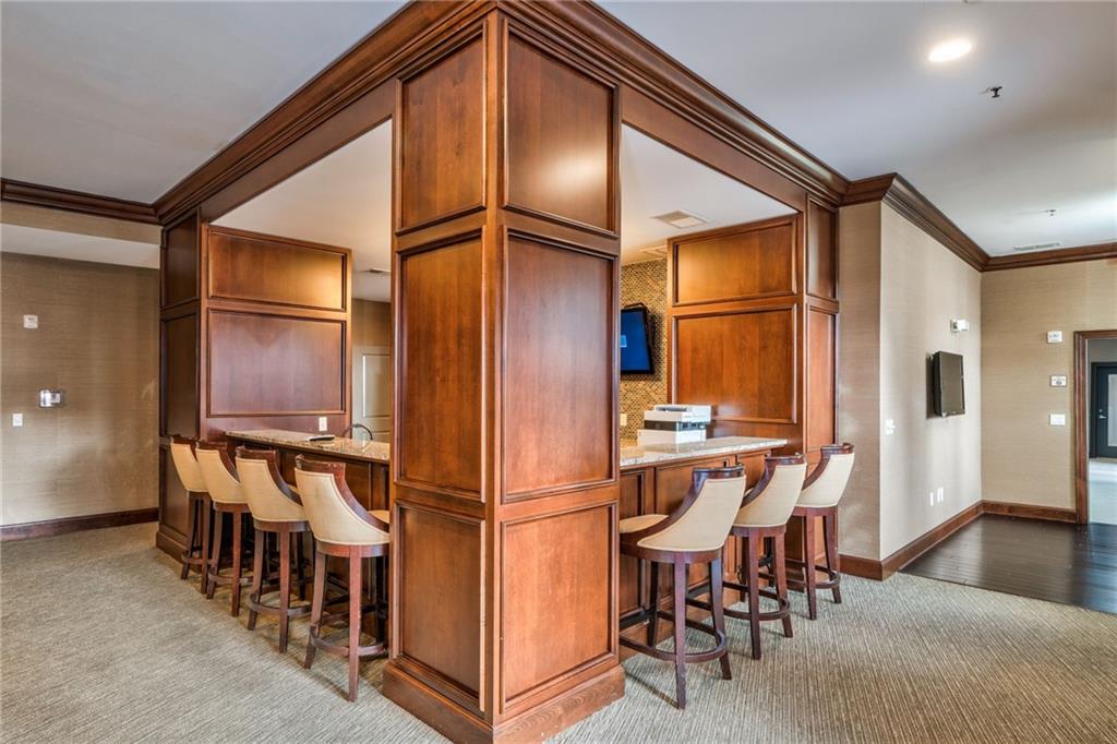 Kitchen featuring a breakfast bar, ornamental molding, light wood-type flooring, and light stone countertops