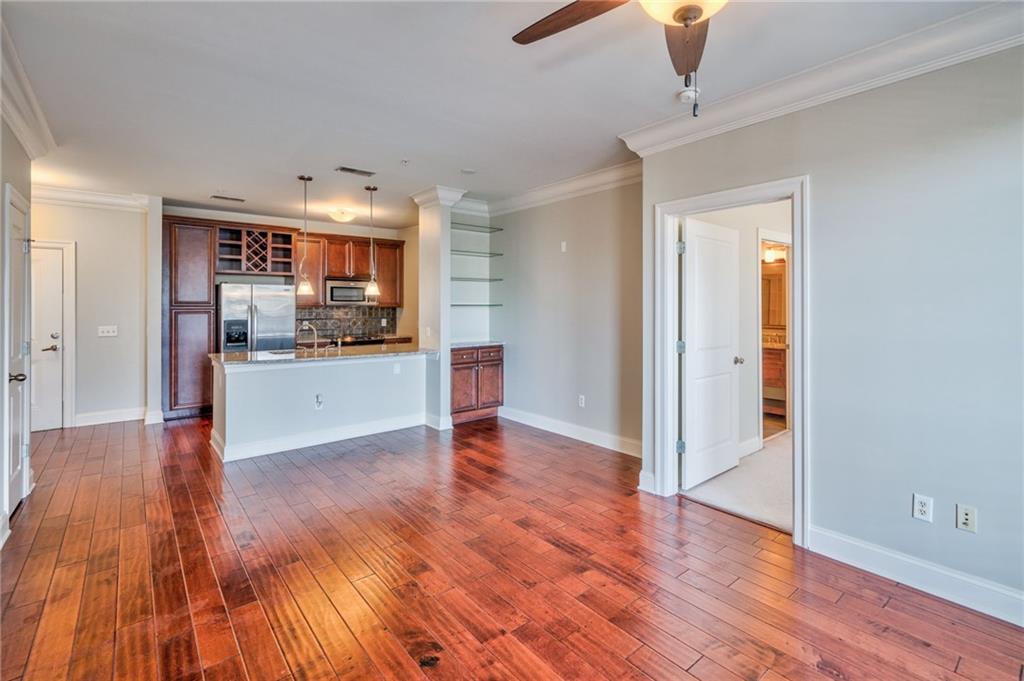 Kitchen with dark wood-type flooring, ceiling fan, appliances with stainless steel finishes, and backsplash