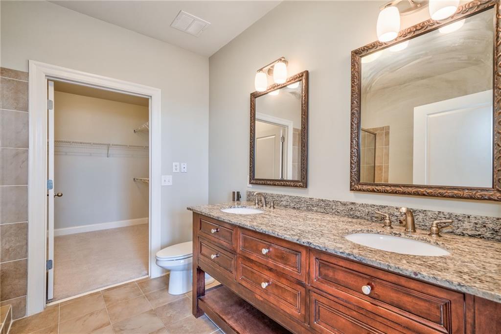 Bathroom with tile floors, double vanity, and toilet