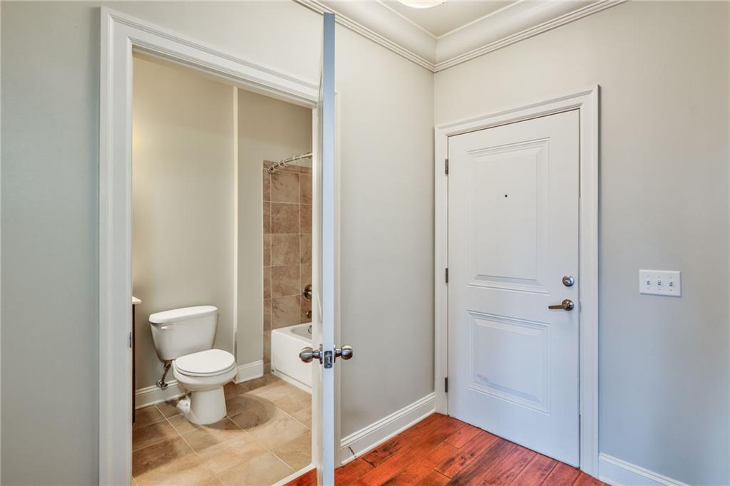 Bathroom with ornamental molding, hardwood / wood-style floors, toilet, and washtub / shower combination