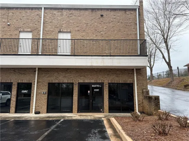 Brick exterior with multiple ground-level entryways and an upper-level balcony featuring black metal railings