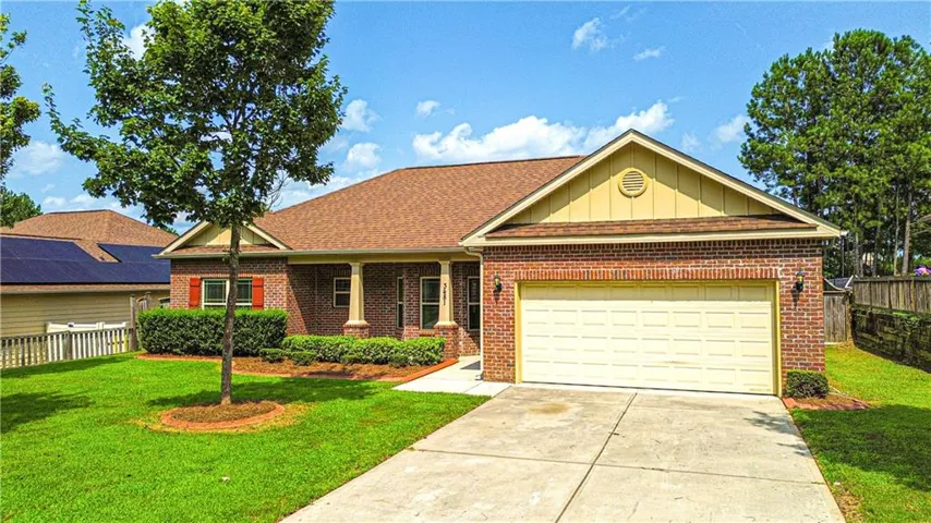 Brick exterior with a two-car garage, covered entry, and a front yard featuring mature landscaping