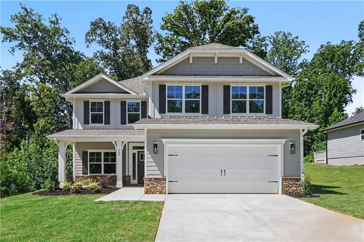 The 2628 plan is a two-story residence, 5/3.5 Primary on Main,  featuring a covered entry, attached two-car garage, stone accents, and exterior wall lanterns