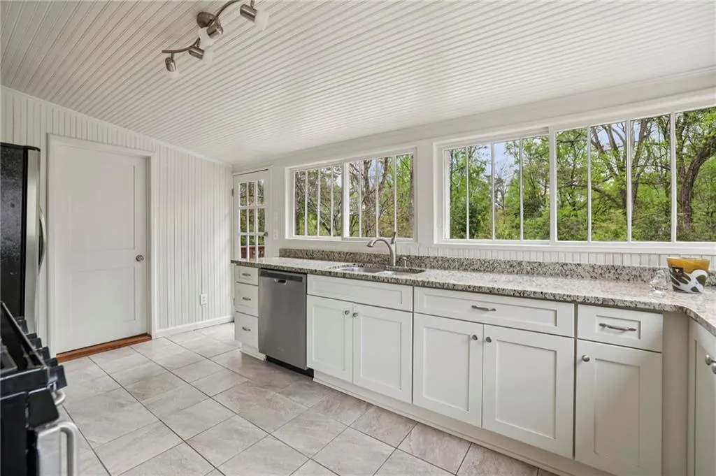 Kitchen with light stone countertops, white cabinets, and a panoramic view of the back yard
