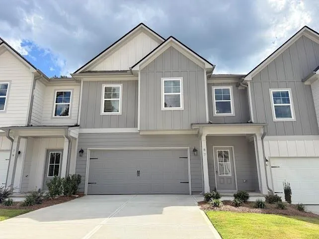 Contemporary townhome exterior featuring a neutral color palette, board and batten siding, a single-car garage, covered entry, and a concrete driveway