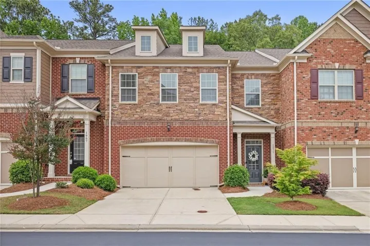 Brick and stone exterior featuring a two-car garage, covered entry, and dormer windows