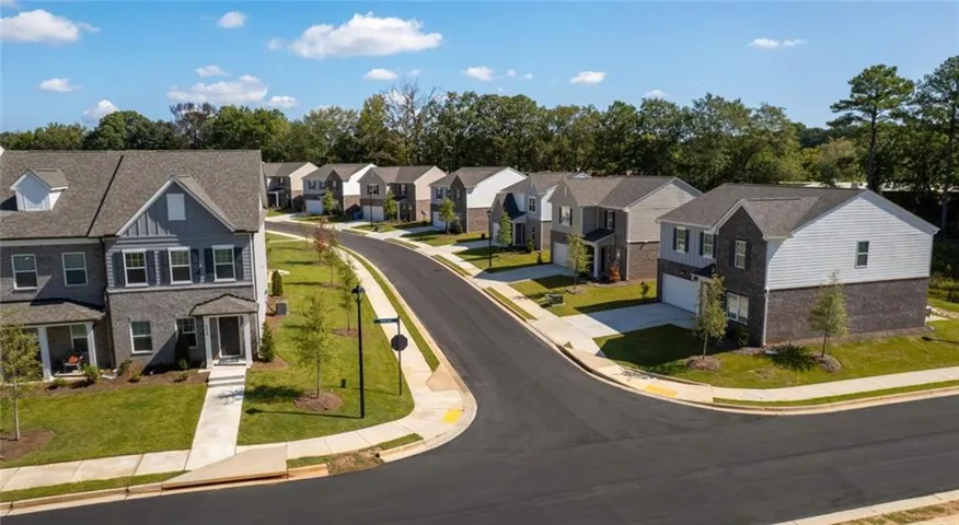 Newly constructed residential street with uniform sidewalks, manicured lawns, and new street lighting