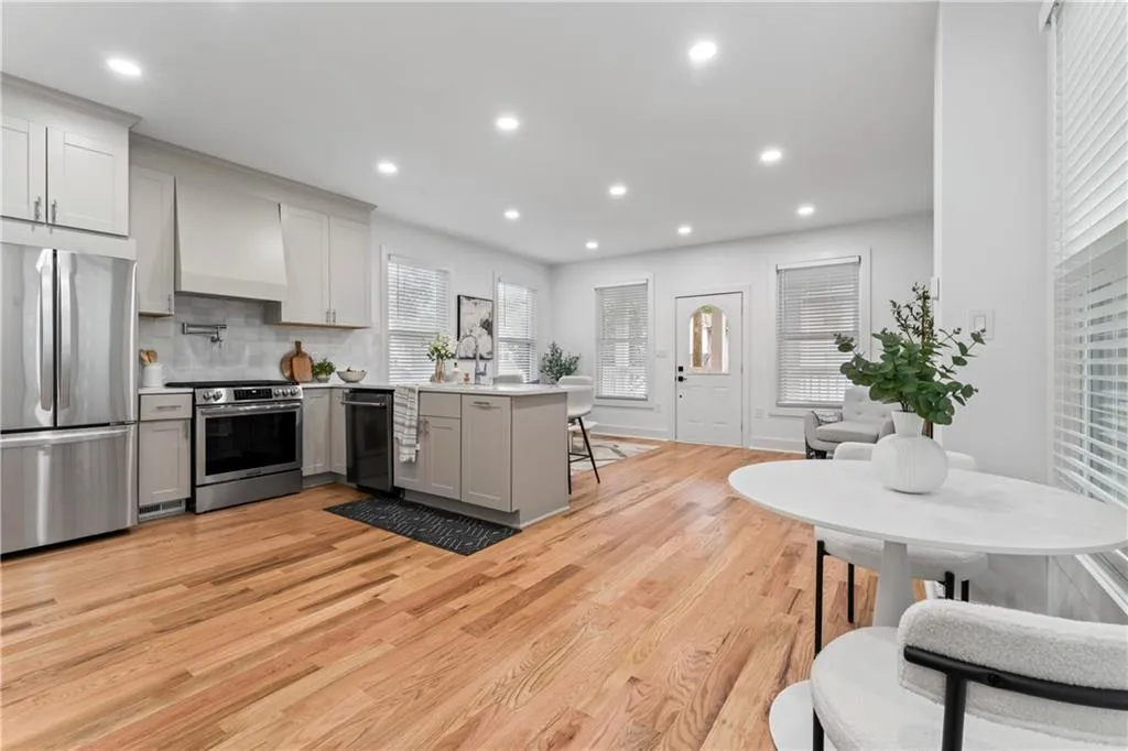 Kitchen with a peninsula, stainless steel appliances, a kitchen bar, gray cabinetry, and light wood finished floors