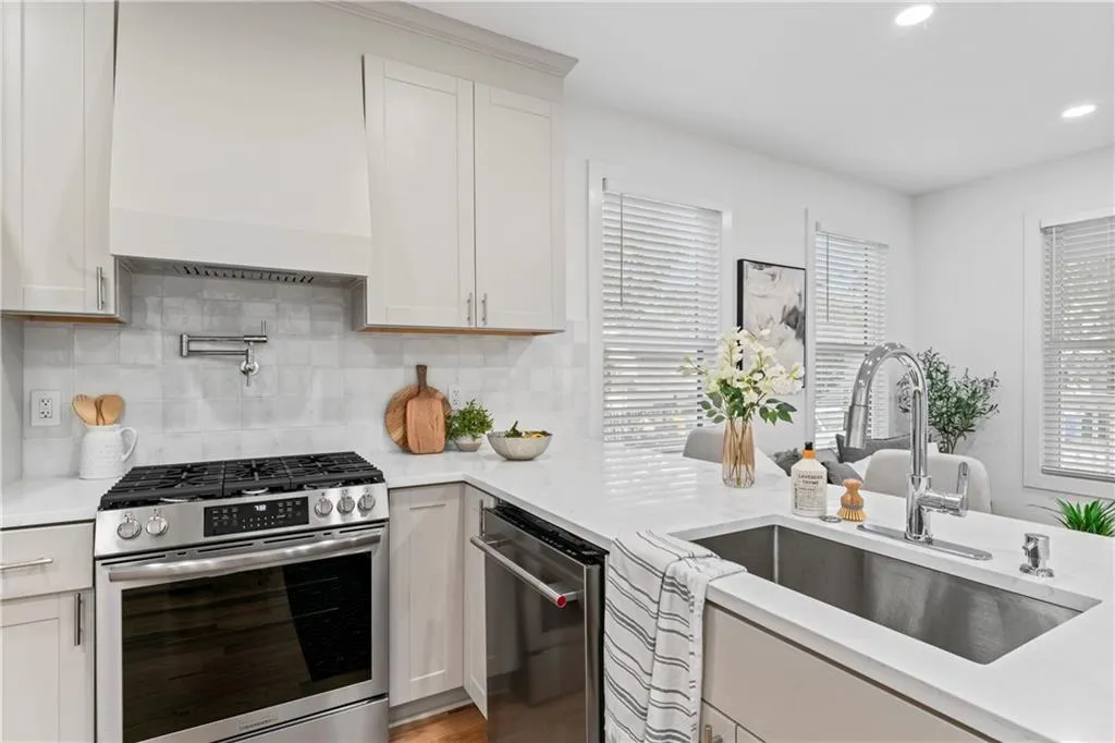 Kitchen with stainless steel appliances, backsplash, recessed lighting, premium range hood, and light stone countertops