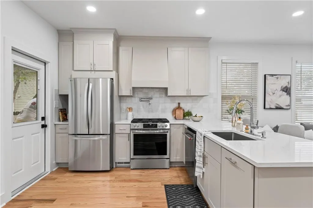 Kitchen with a peninsula, stainless steel appliances, light stone counters, light wood-style floors, and recessed lighting