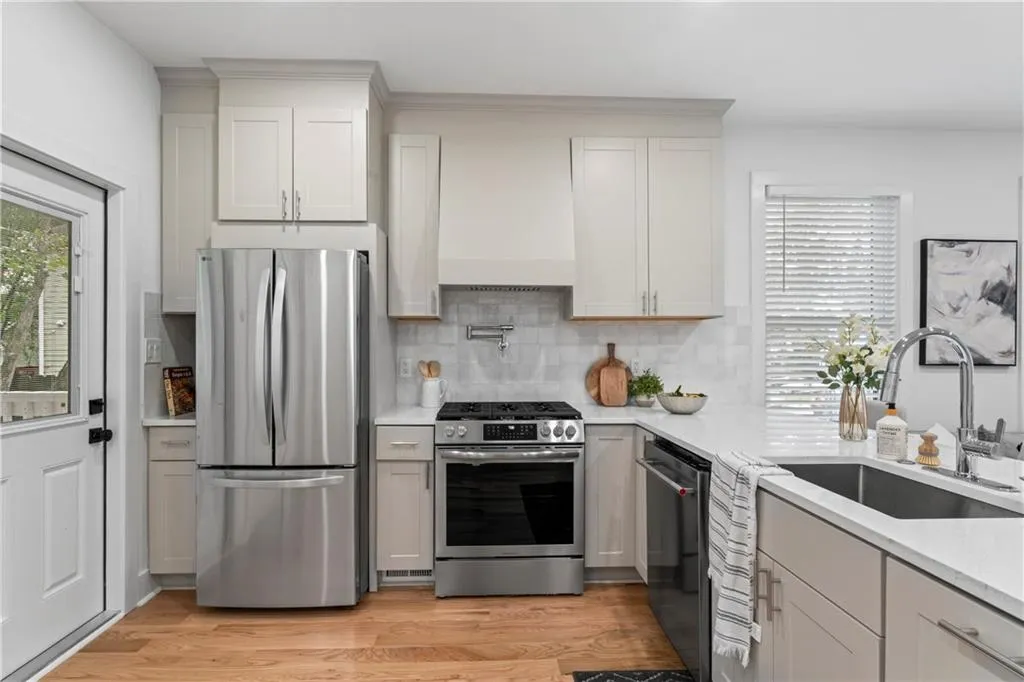 Kitchen featuring plenty of natural light, appliances with stainless steel finishes, light wood finished floors, and light stone countertops