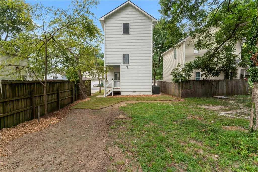 Rear view of property with a fenced backyard and crawl space. Fence and landscaping completed after photos.