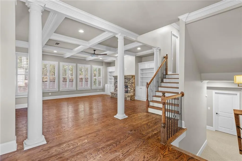 Living room featuring coffered ceiling, ornate columns, beam ceiling, ceiling fan, and recessed lighting