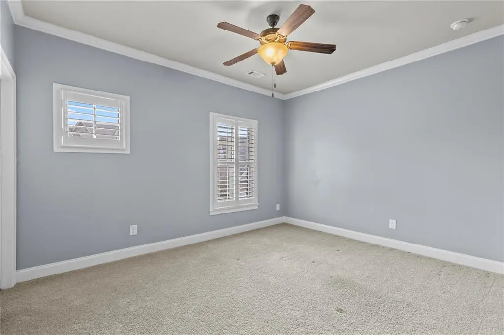 Carpeted spare room with ornamental molding and a ceiling fan