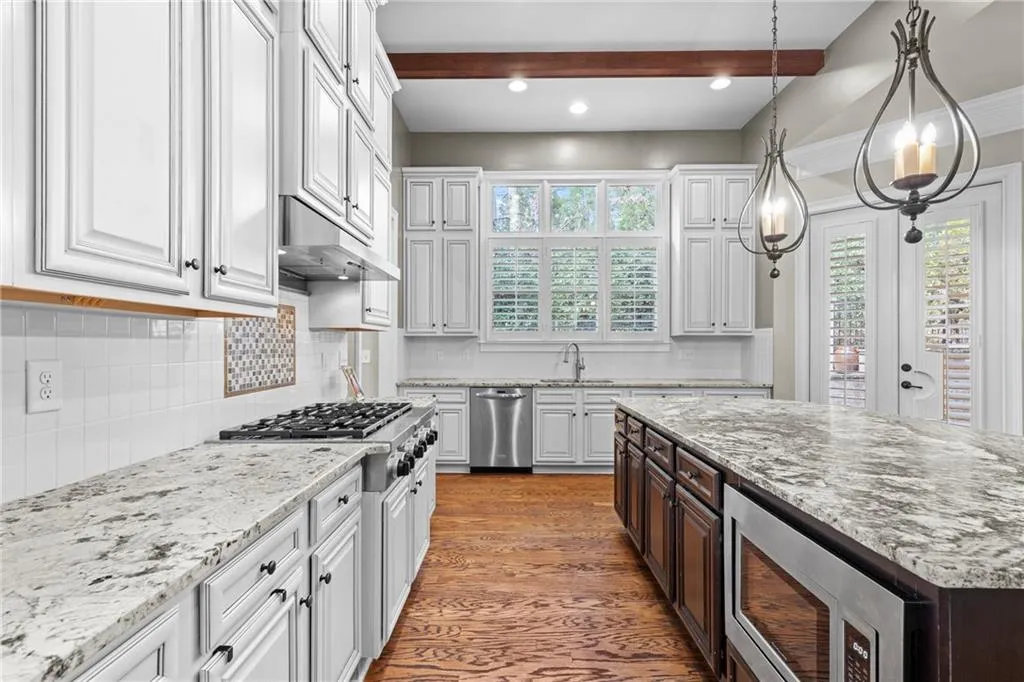 Kitchen with dark brown cabinets, light stone counters, appliances with stainless steel finishes, white cabinets, and recessed lighting