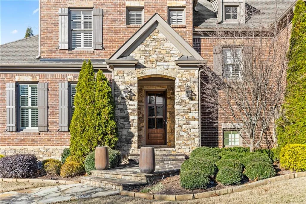Property entrance with brick siding, stone siding, and a shingled roof