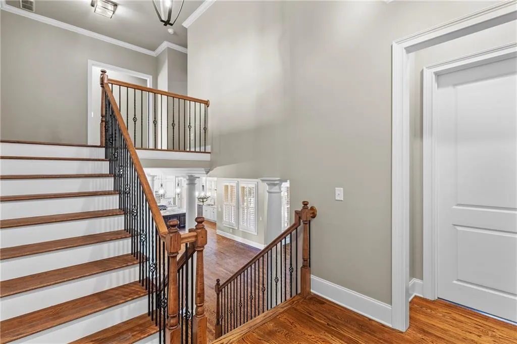 Stairs featuring ornamental molding, wood finished floors, a chandelier, and a high ceiling