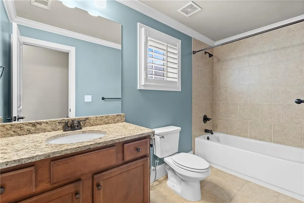Bathroom featuring tub / shower combination, vanity, ornamental molding, and light tile patterned floors