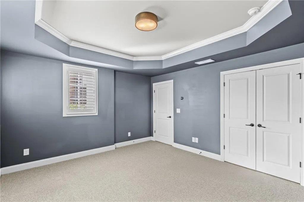 Unfurnished bedroom featuring crown molding, carpet flooring, a raised ceiling, and a closet