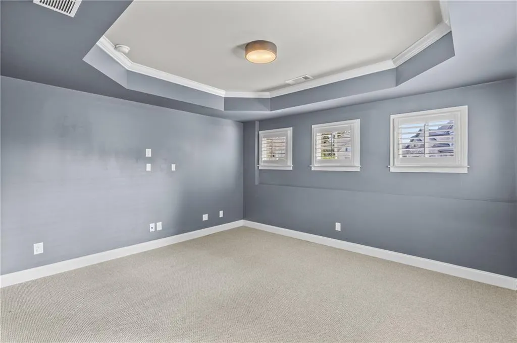 Carpeted spare room with crown molding and a tray ceiling